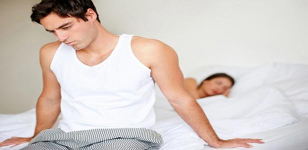 man on bed battling with erectile dysfunction